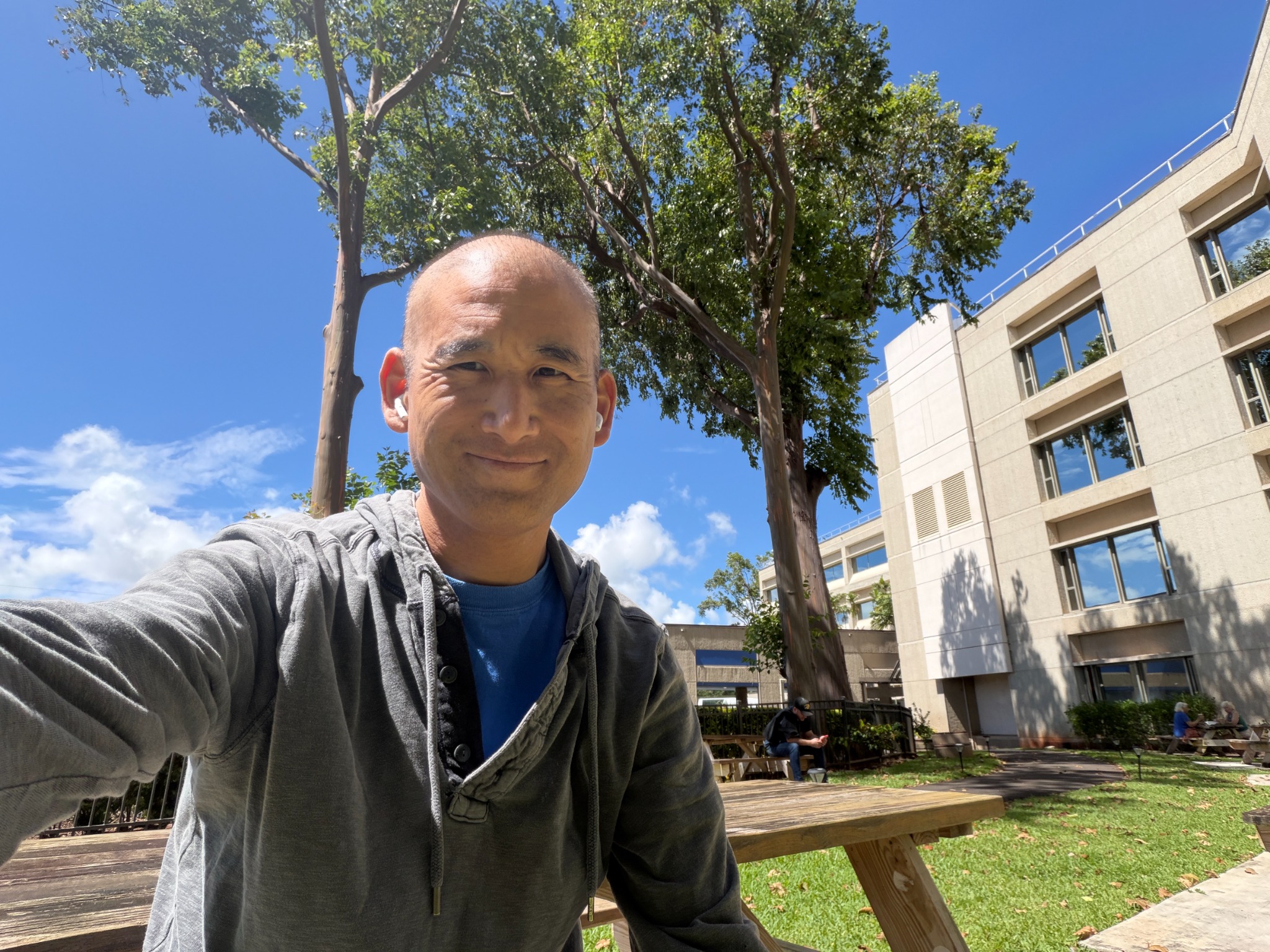 Dr. David Kato smiling outdoors beneath a tree